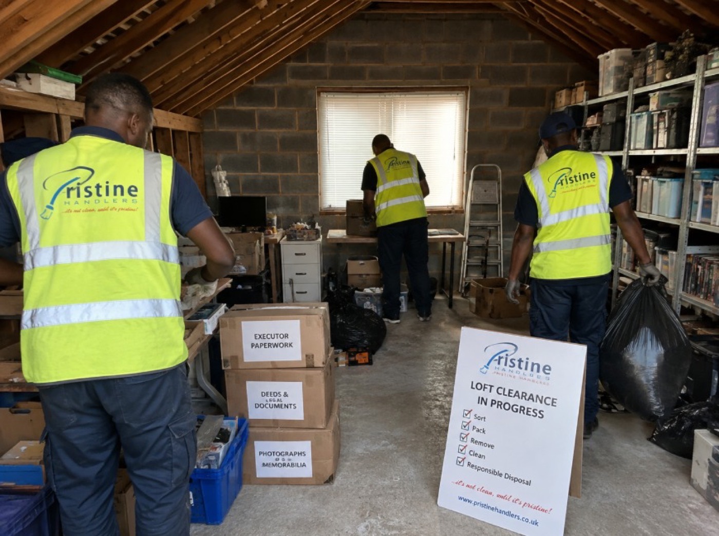 Crew in branded hi-vis clearing and sorting a loft into labelled boxes
